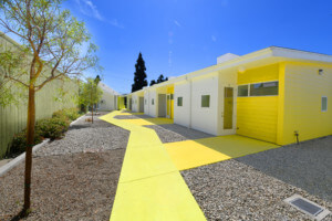 a bring yellow housing complex with units linked by a parth