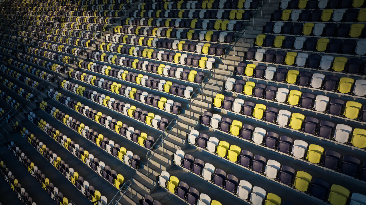 empty seating, in yellow, purple, and white, at a soccer stadium