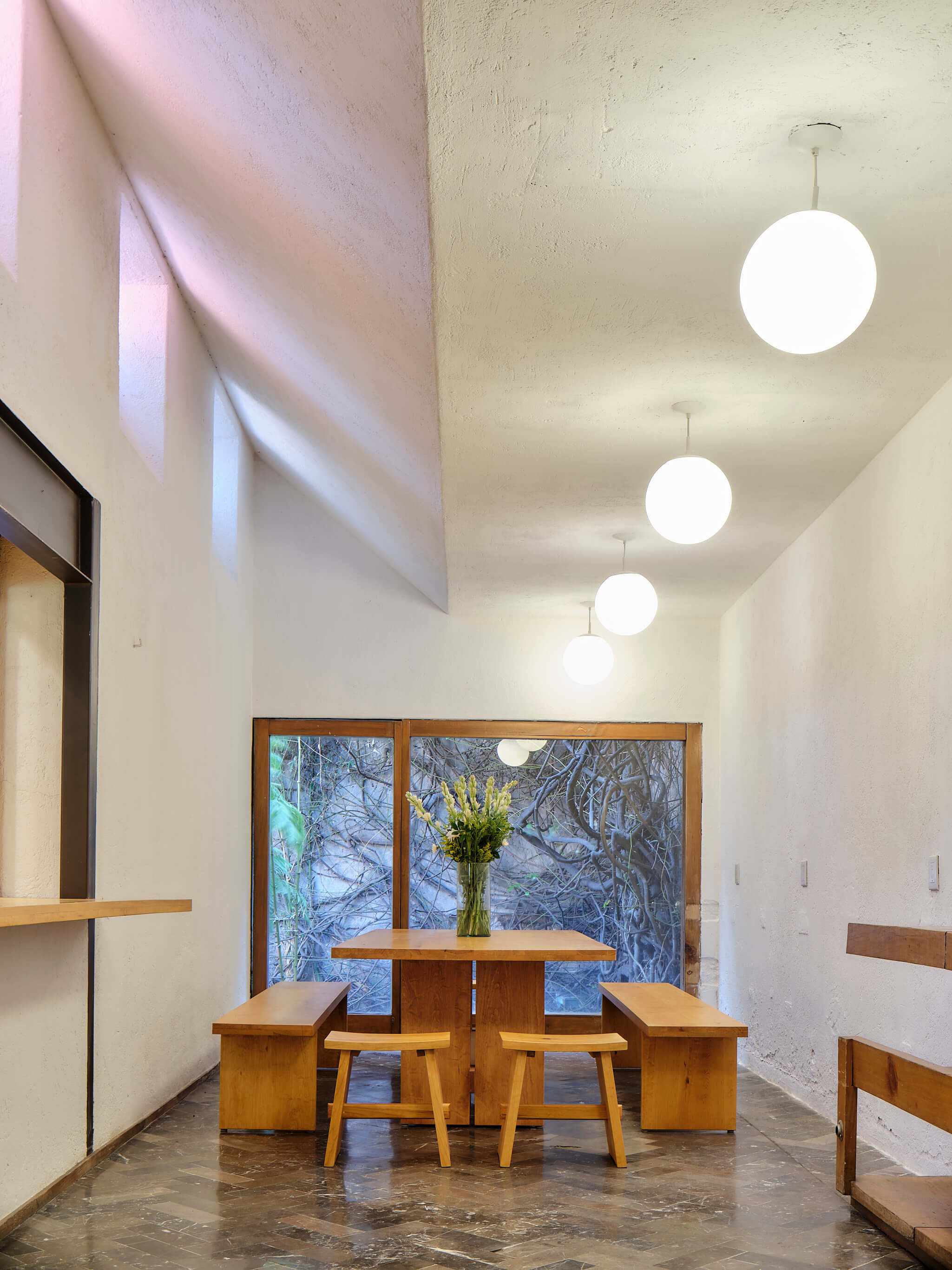 A simple dining room with a slanted roof and wooden table and chairs