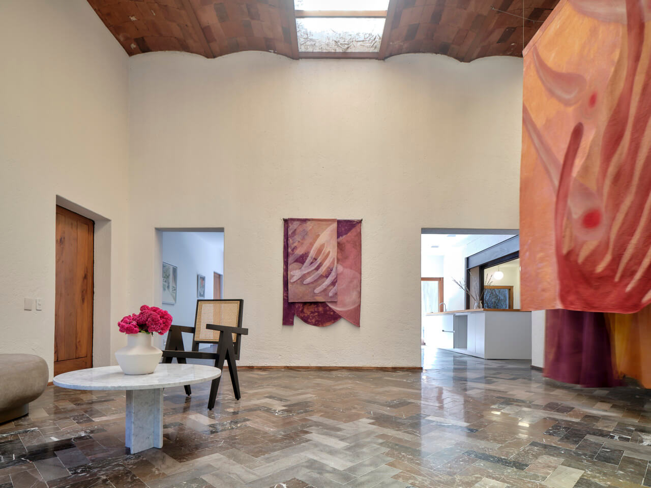 A gallery space with herringbone floors and vaulted ceilings inside of JO-HS
