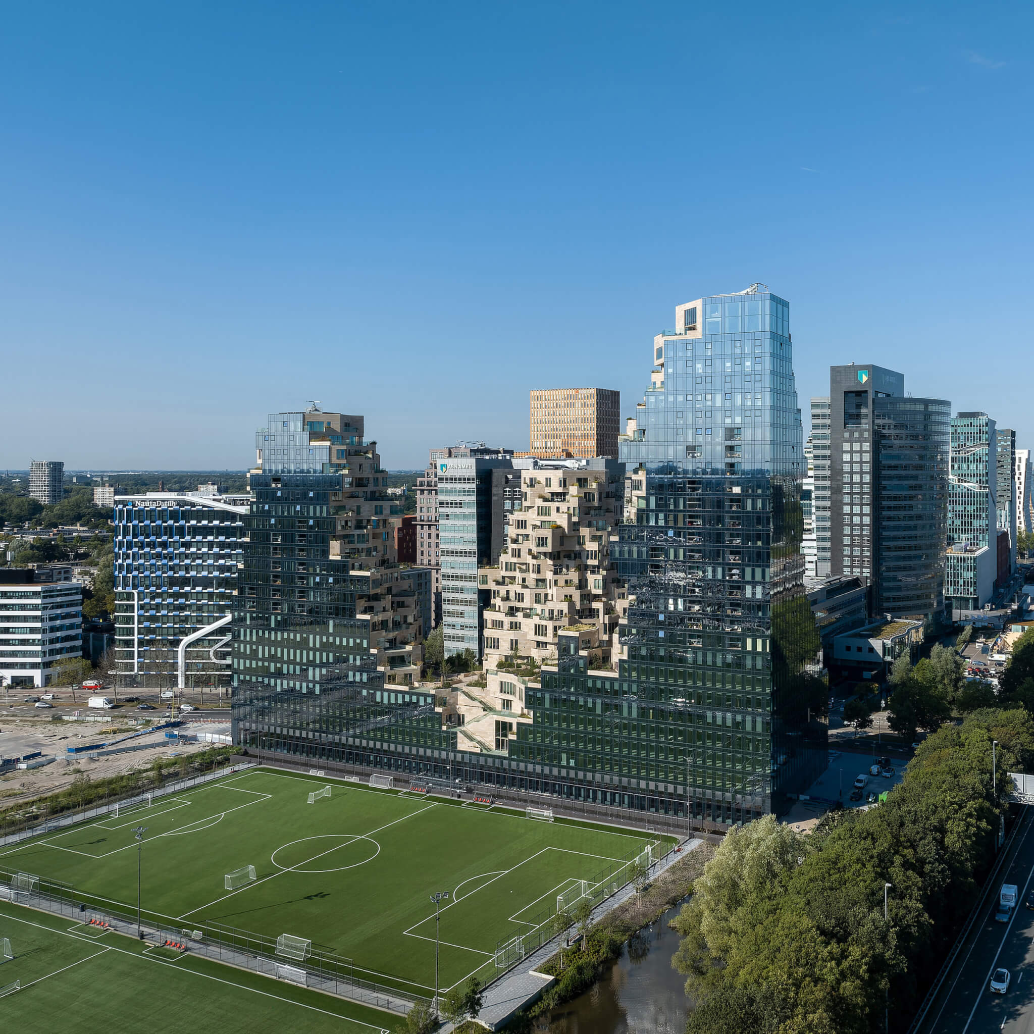jagged towers clad in reflective glass rising over a football pitch