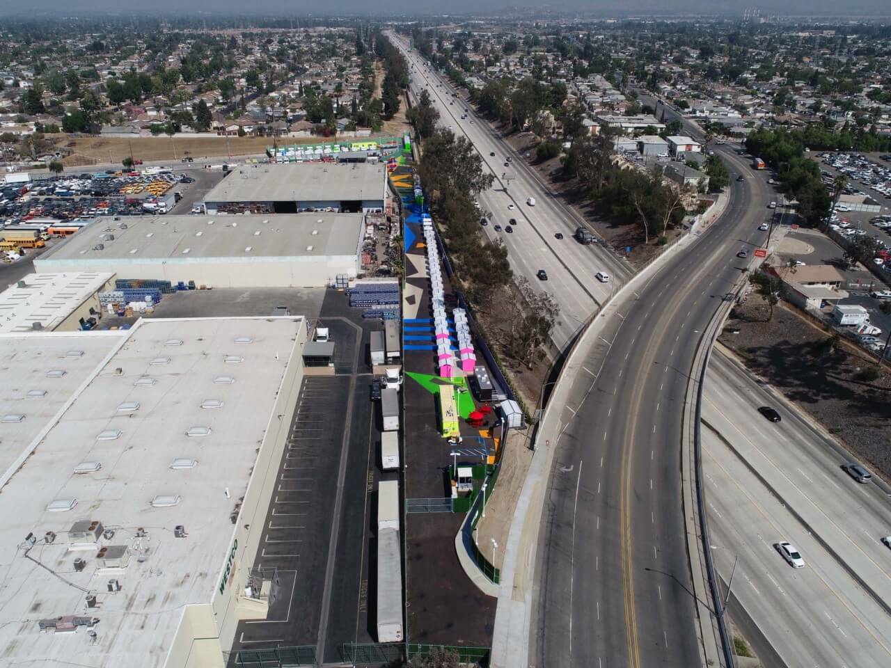 a brightly colored tiny house community located alongside a freeway