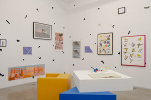 photograph of a gallery interior with several drawings and artworks mounted to the walls
