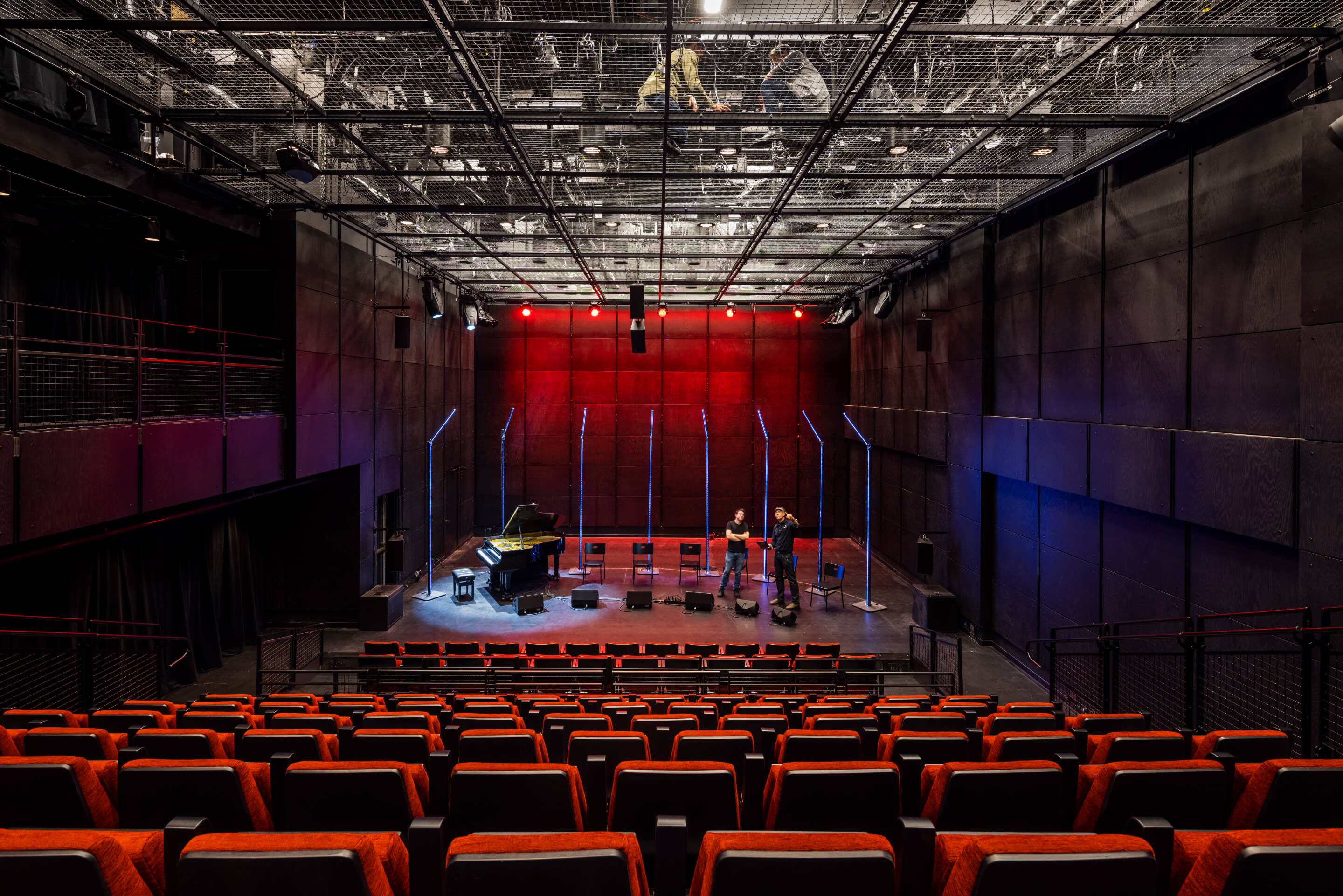 inside a large black box theater looking at the stage with cage above