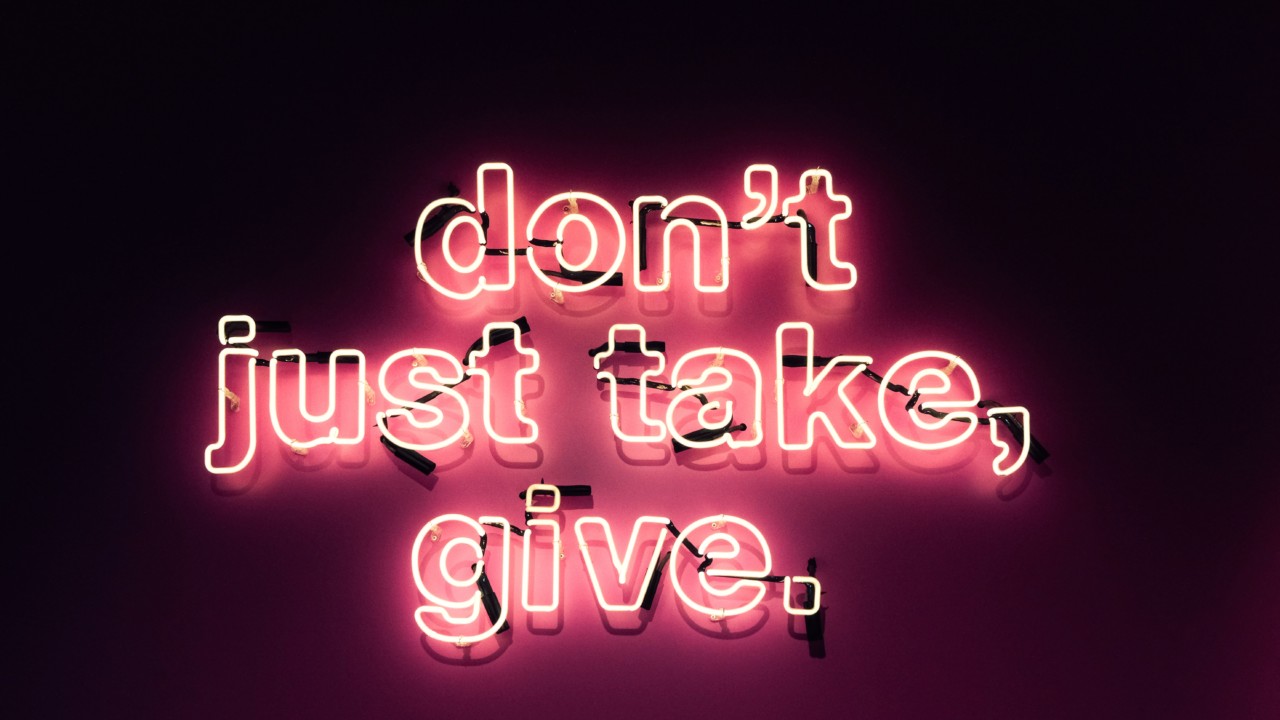 an illuminated sign reading "don't just take, give", to illuminate our giving guide
