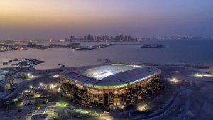 nighttime aerial view of a soccer stadium partially built with stacked shipping containers for the 2022 FIFA World Cup