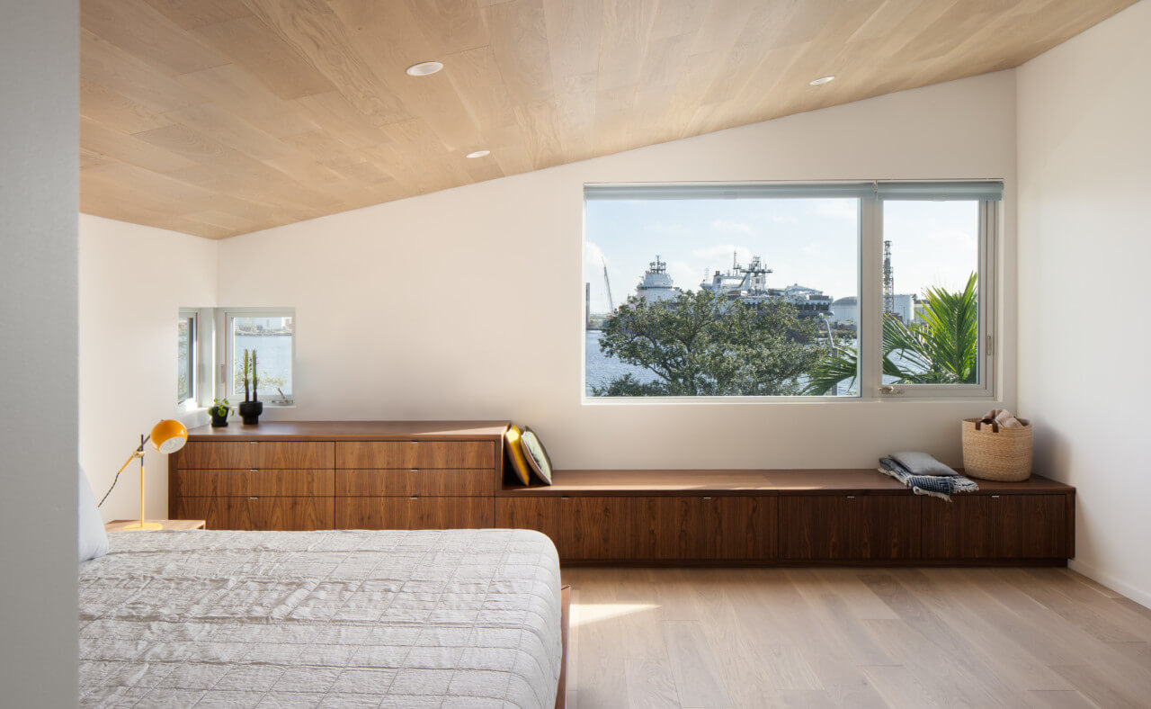 A sloping timber roof over a white bedroom