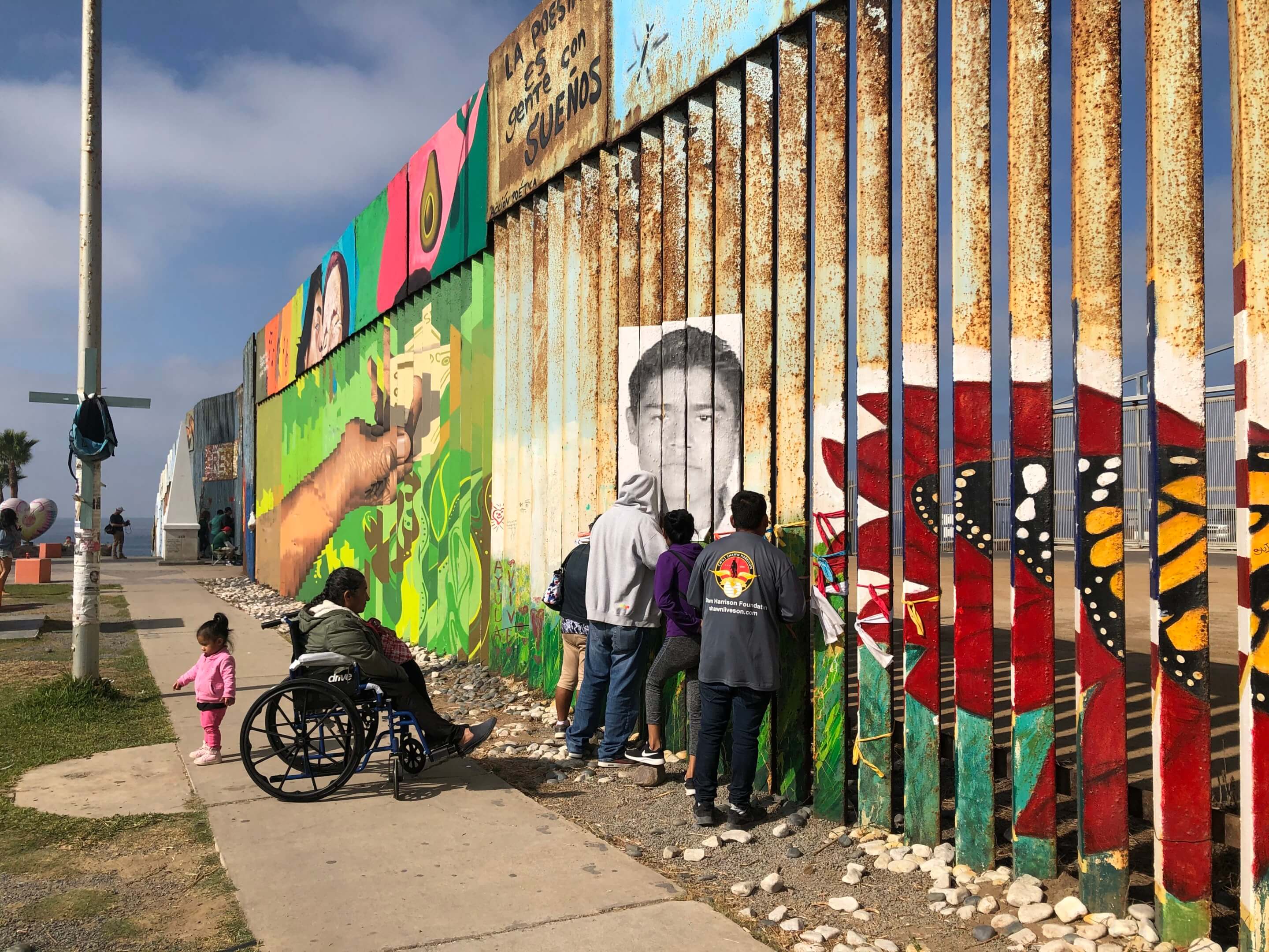 Children at a line of steel slats covered in murals