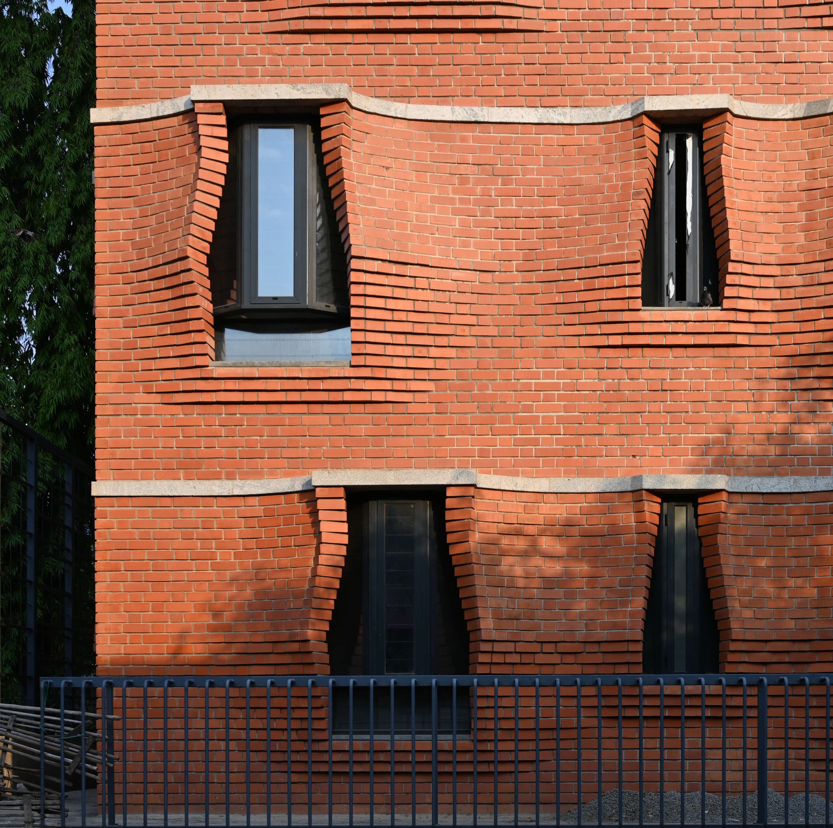 A brick facade splayed open with windows peeking through