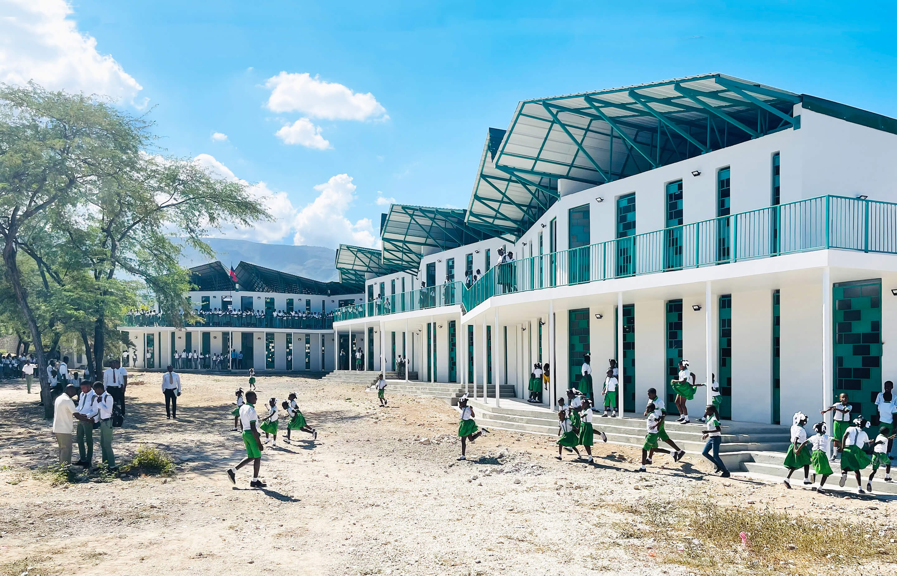 children in uniforms play outside of a rural school building