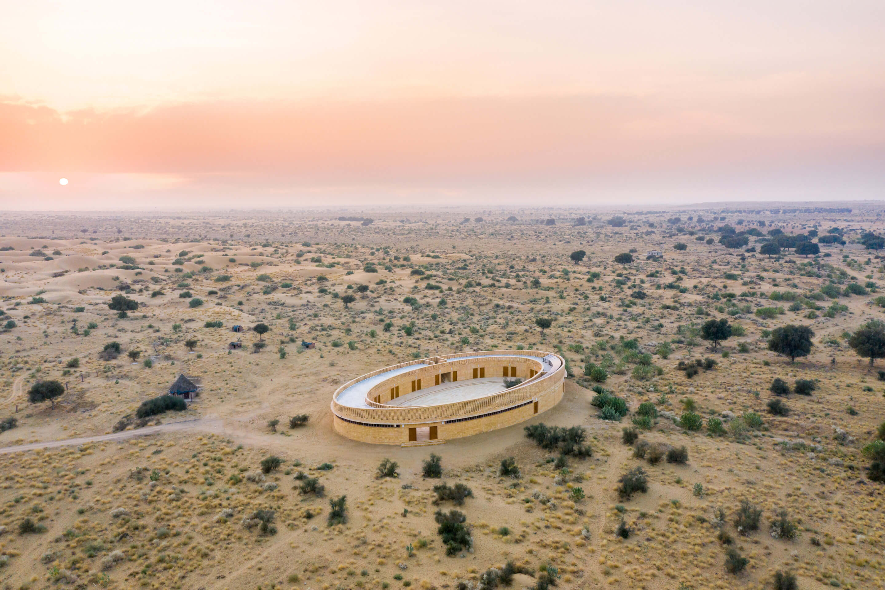 a circular building surrounded by a vast, empty desert landscape