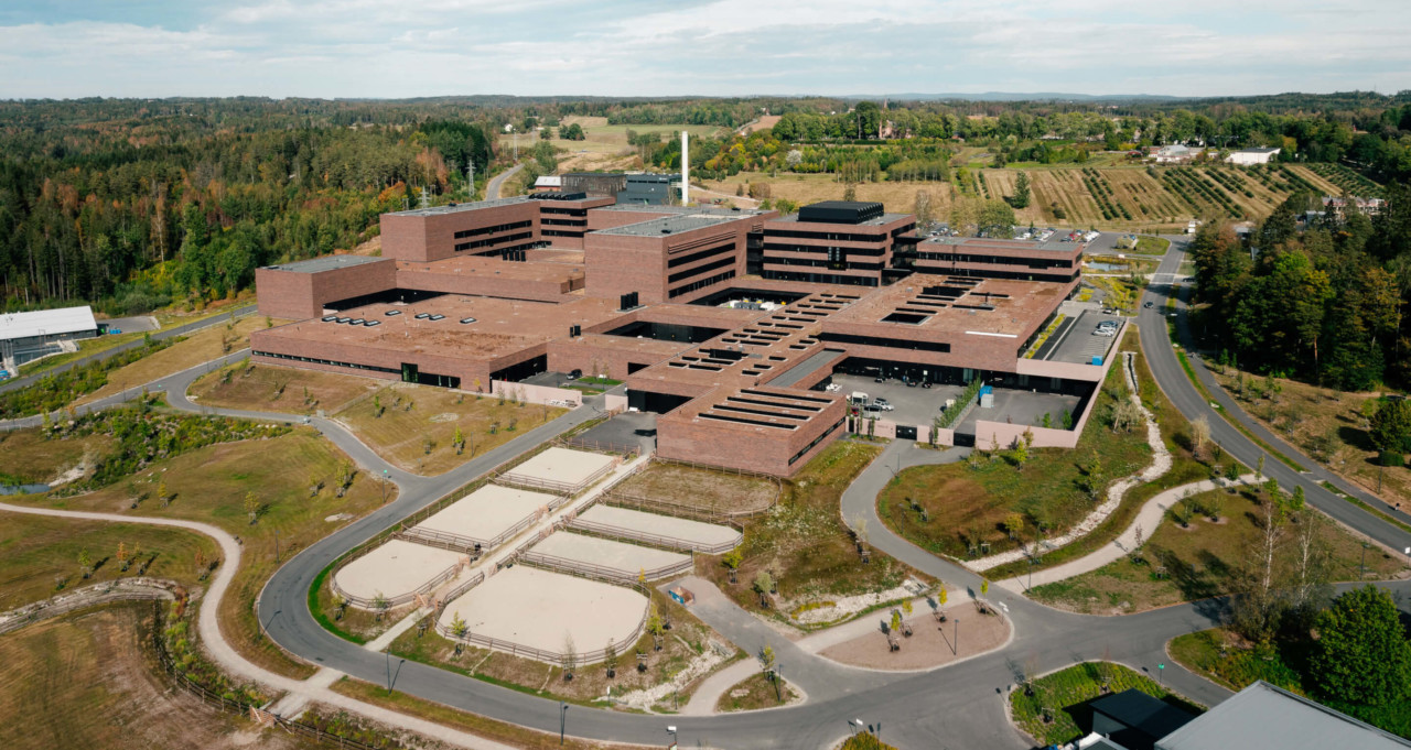 aerial view of a vast brick educational and research building flanked by open space designed by henning larsen