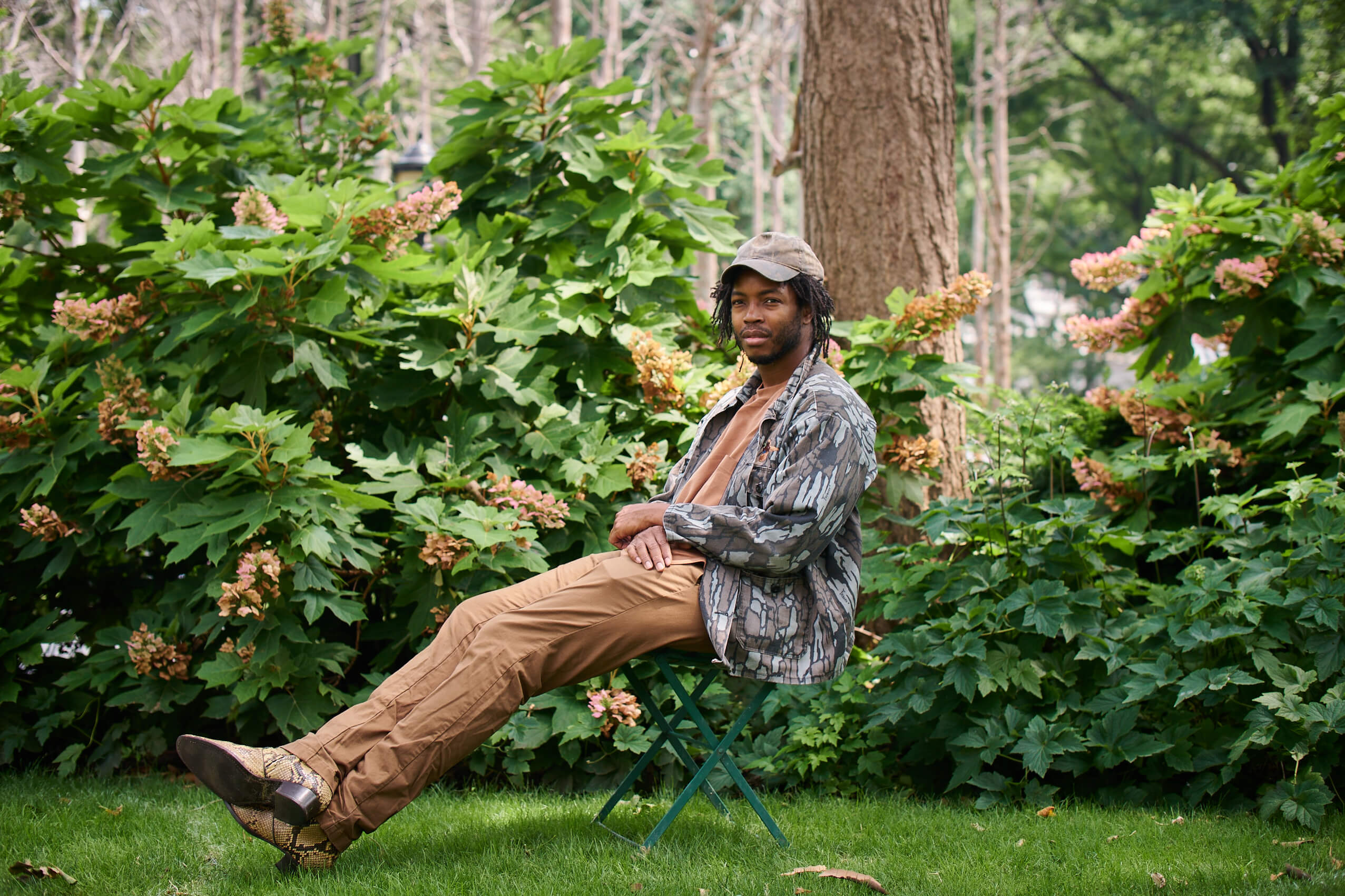 artist hugh hayden sitting in a lush park