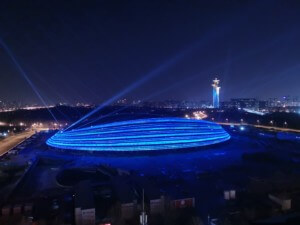 view of a oval arena building illuminated in blue light
