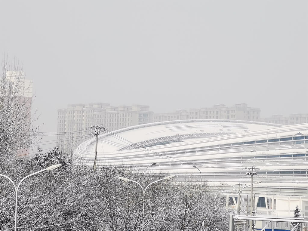 exterior of a large, oval arena building covered in a blanket of snow