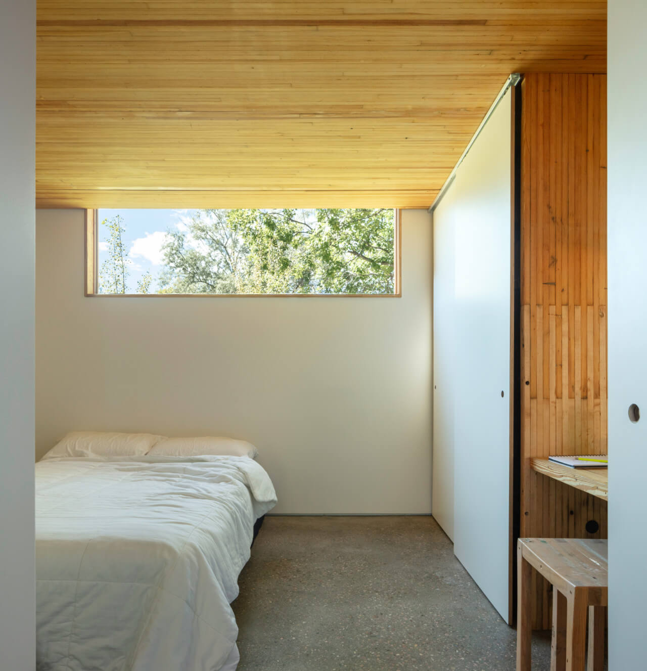 A bedroom in a white room with timber ceiling