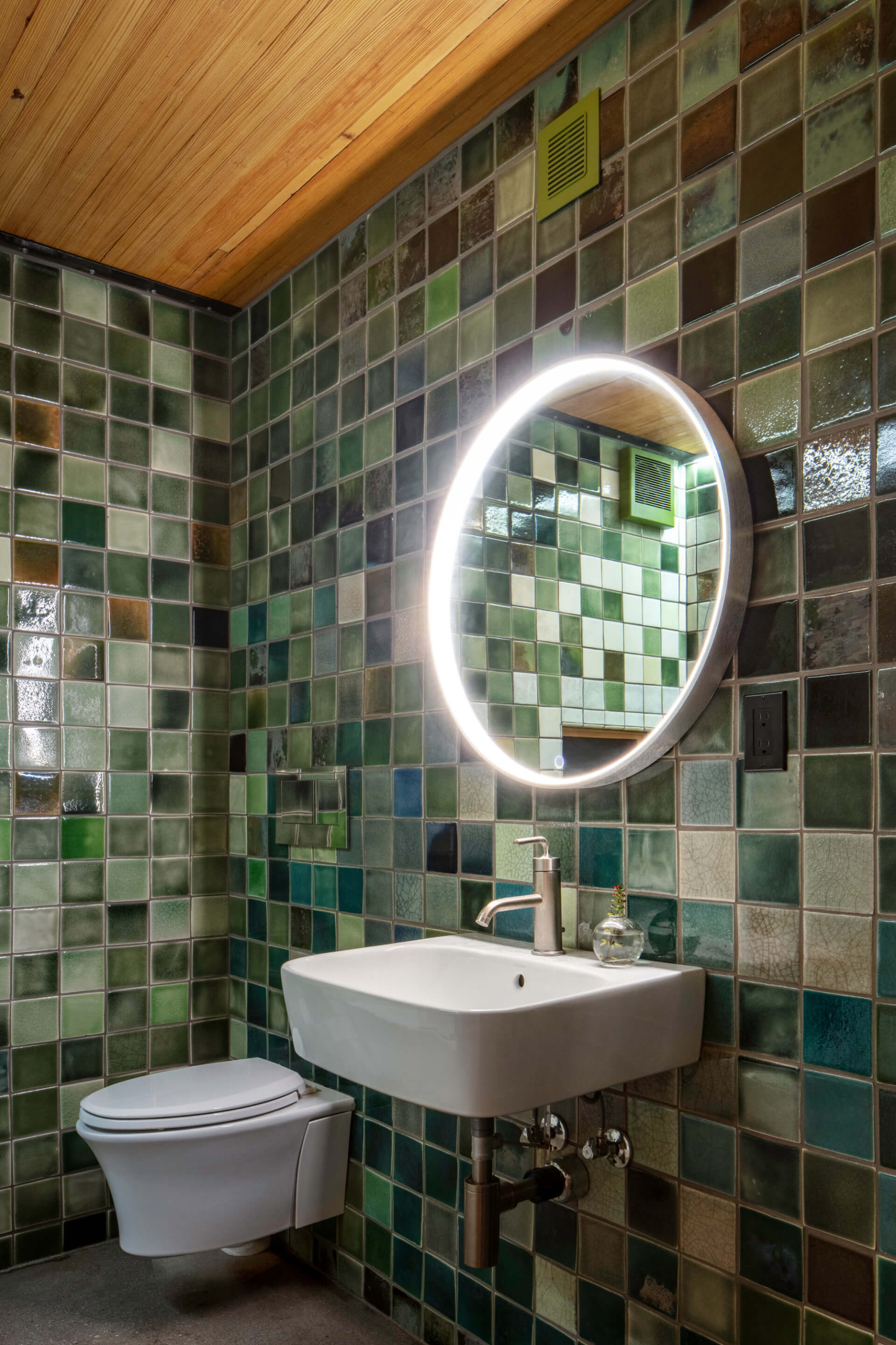 Interior of a bathroom with green tile designed by tres birds