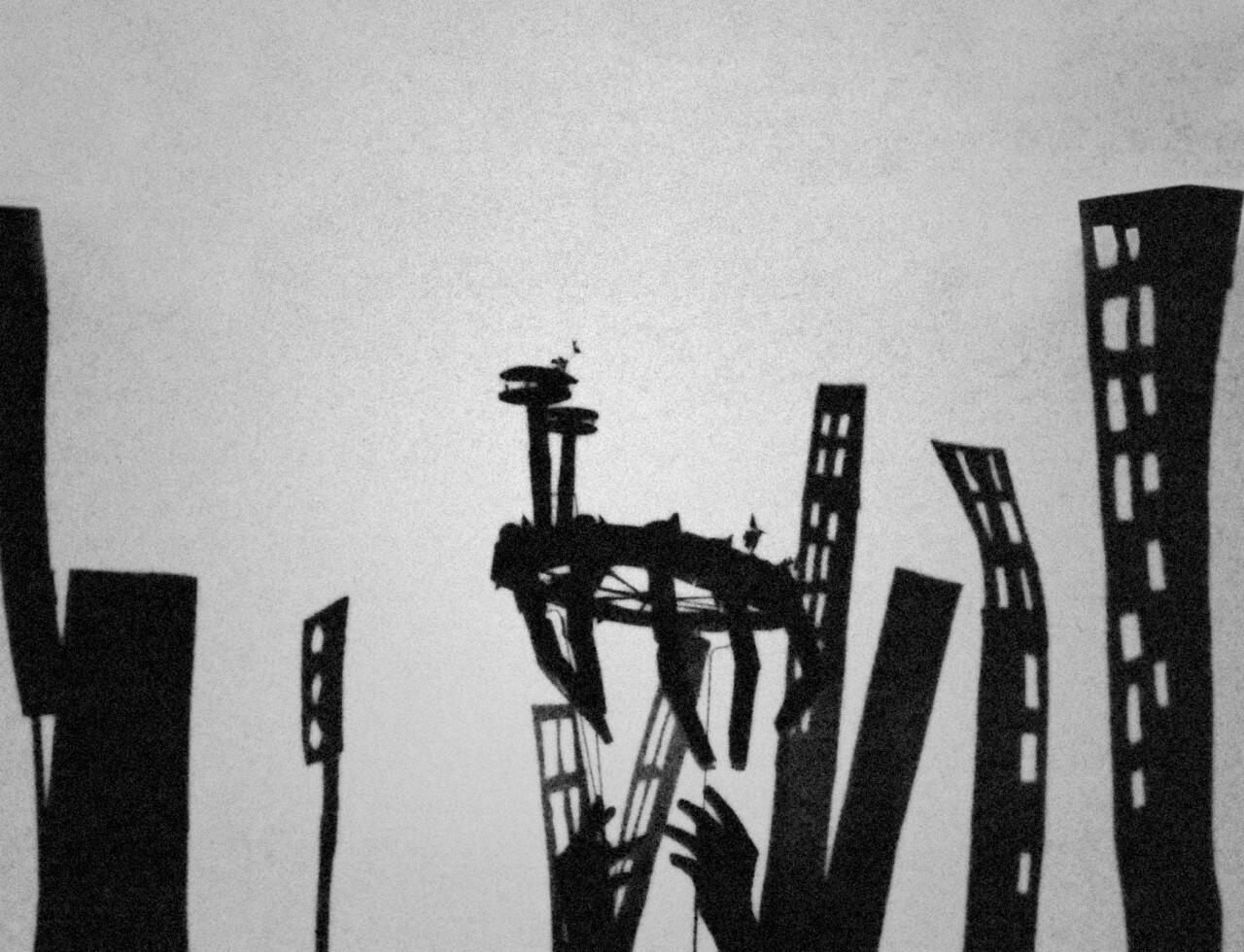 a film still depicting shadows of a puppeteer’s hands and miniature buildings in the great ruins of saturn