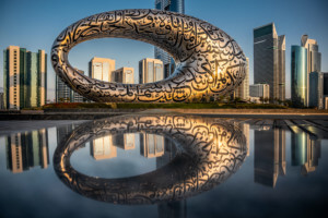 a ring-shaped building reflected in a nearby lake