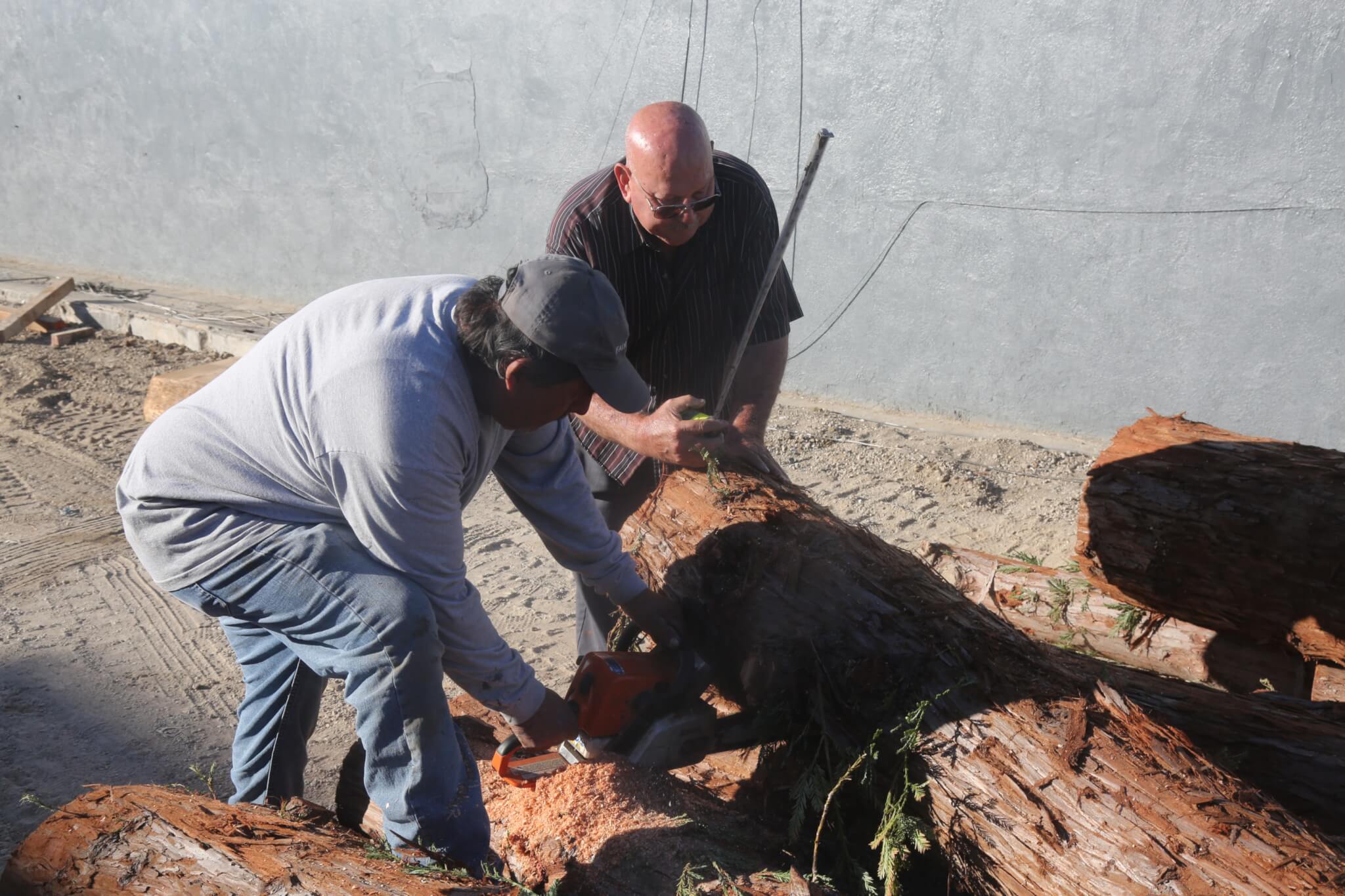 two workers push logs into place for a garden project