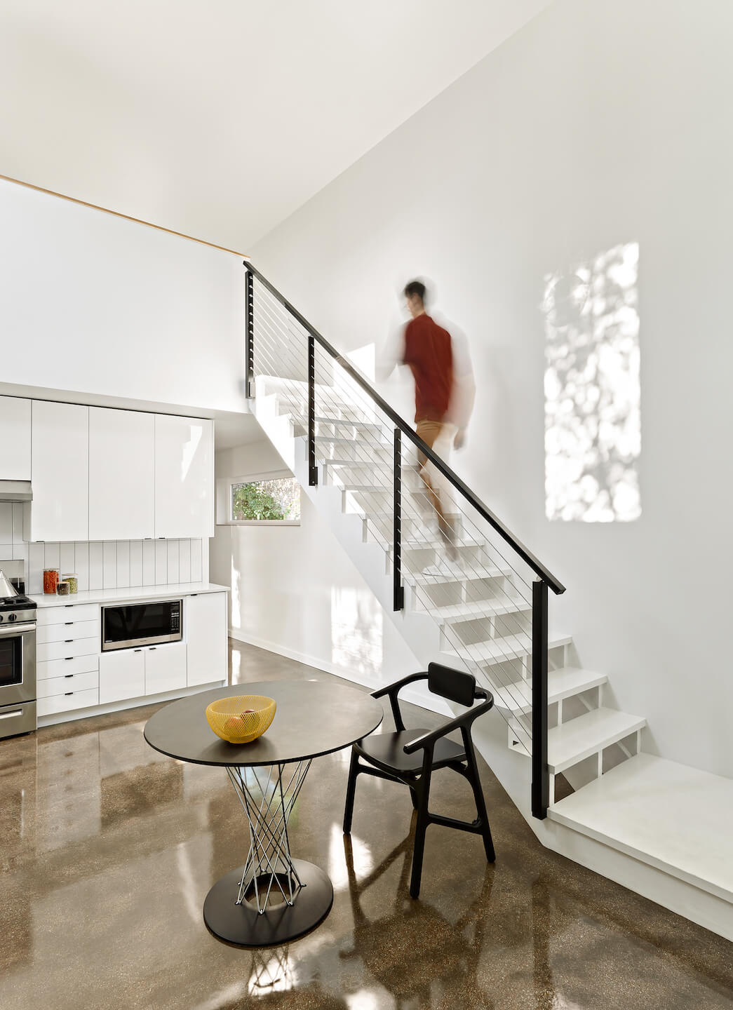 view of a contemporary open kitchen space with a man ascending a staircase