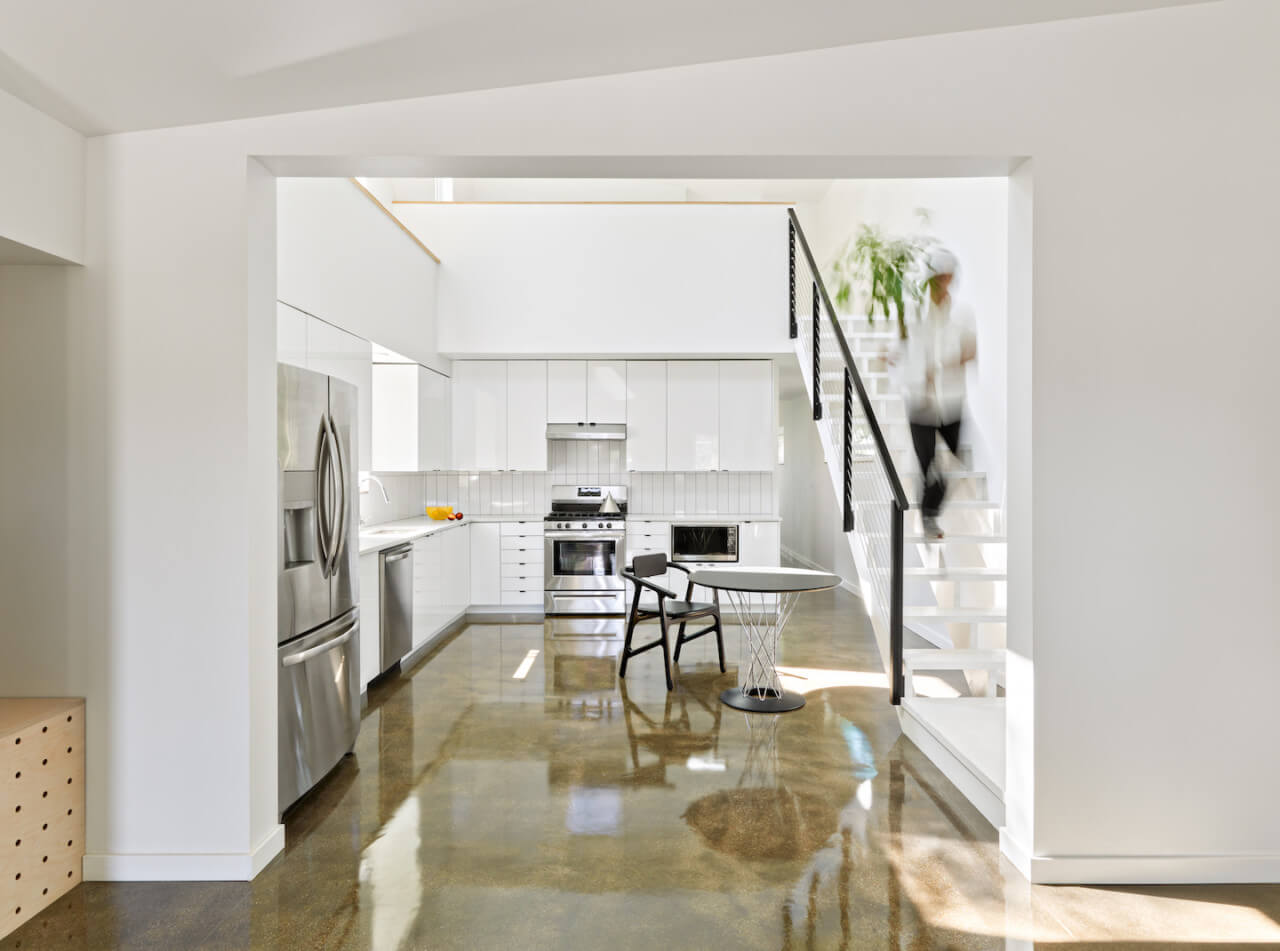 interior view of a open contemporary living area an kitchen with bright white walls