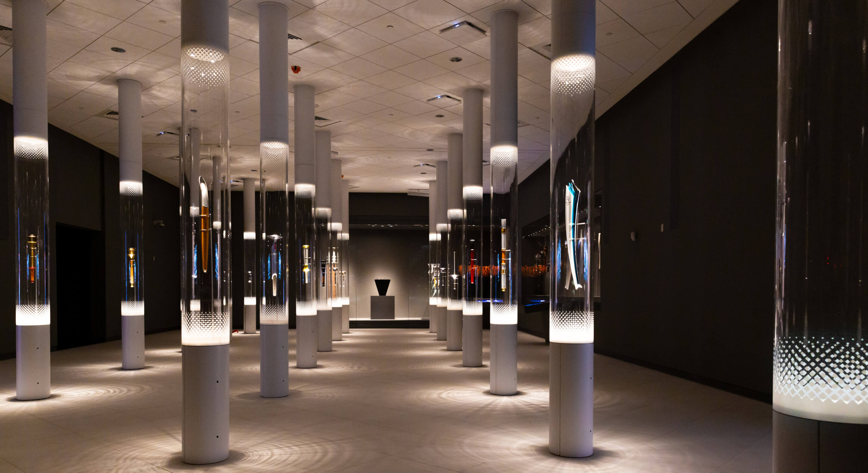 a museum exhibit featuring olympic torches in cylindrical displays