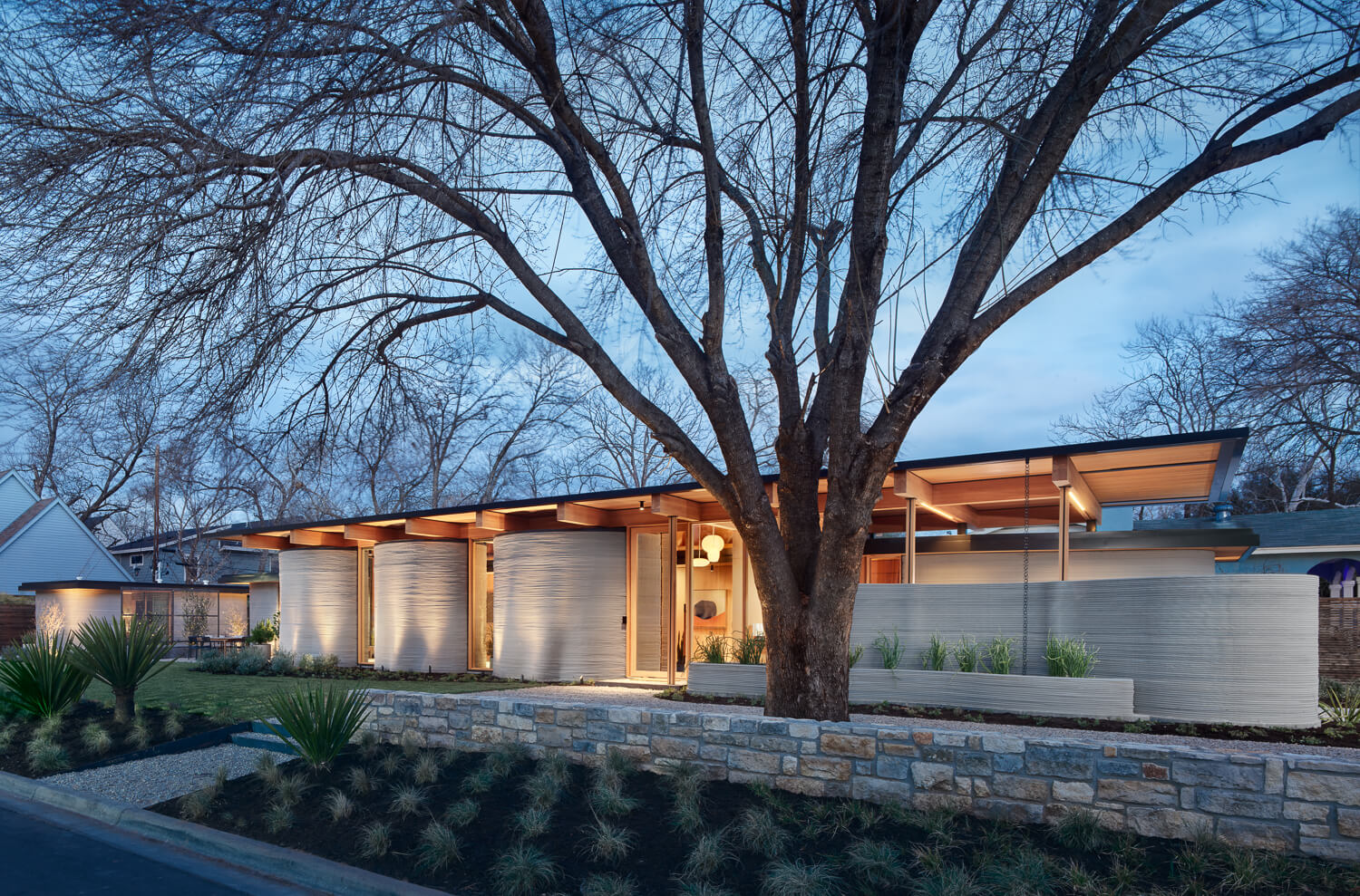 exterior of a ranch-style 3d-printed home with concrete walls and timber roof structure