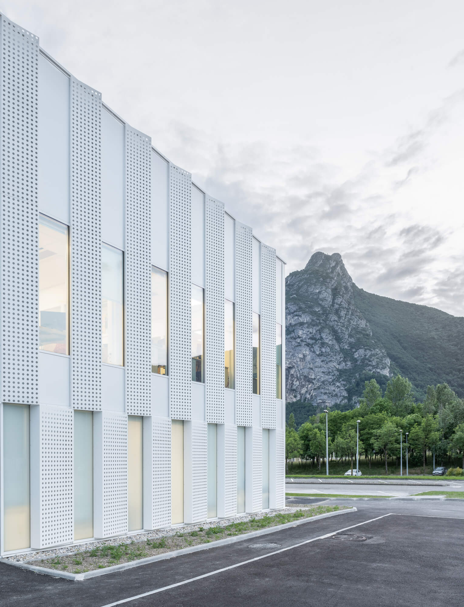 A white building with angular facade patterns with a mountain in the background