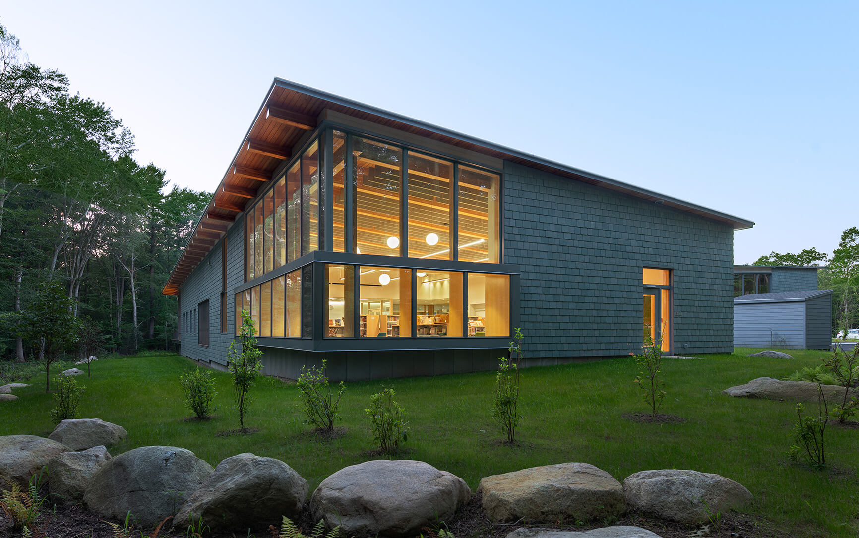 exterior view of a mass timber library building surrounded by a lush lawn
