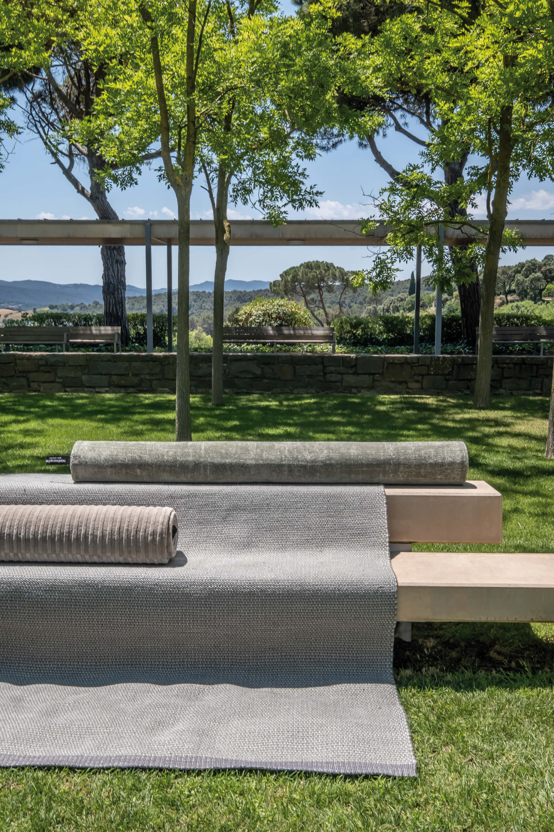 Grey fabric draped over an outdoor bench in a park with mountains in the background