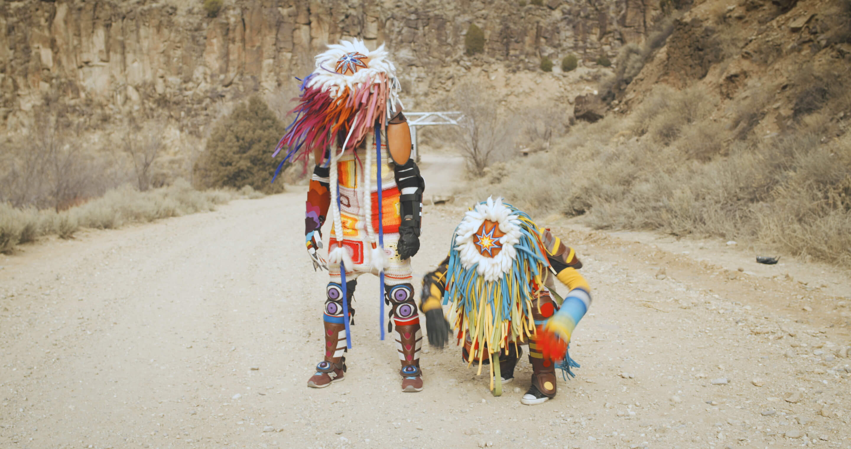 two people in a desert landscape wearing colorful costumes