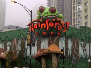 garish storefront featuring giant green frog with red eyes posed over a sign that says Rainforest Cafe