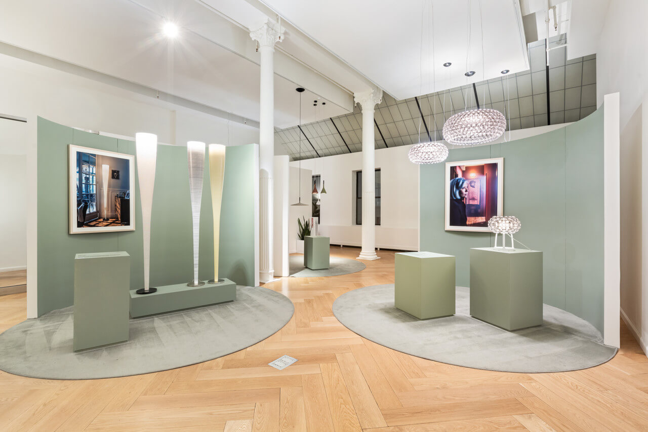 pale green-walled showroom featuring photos and lamps on pedestals