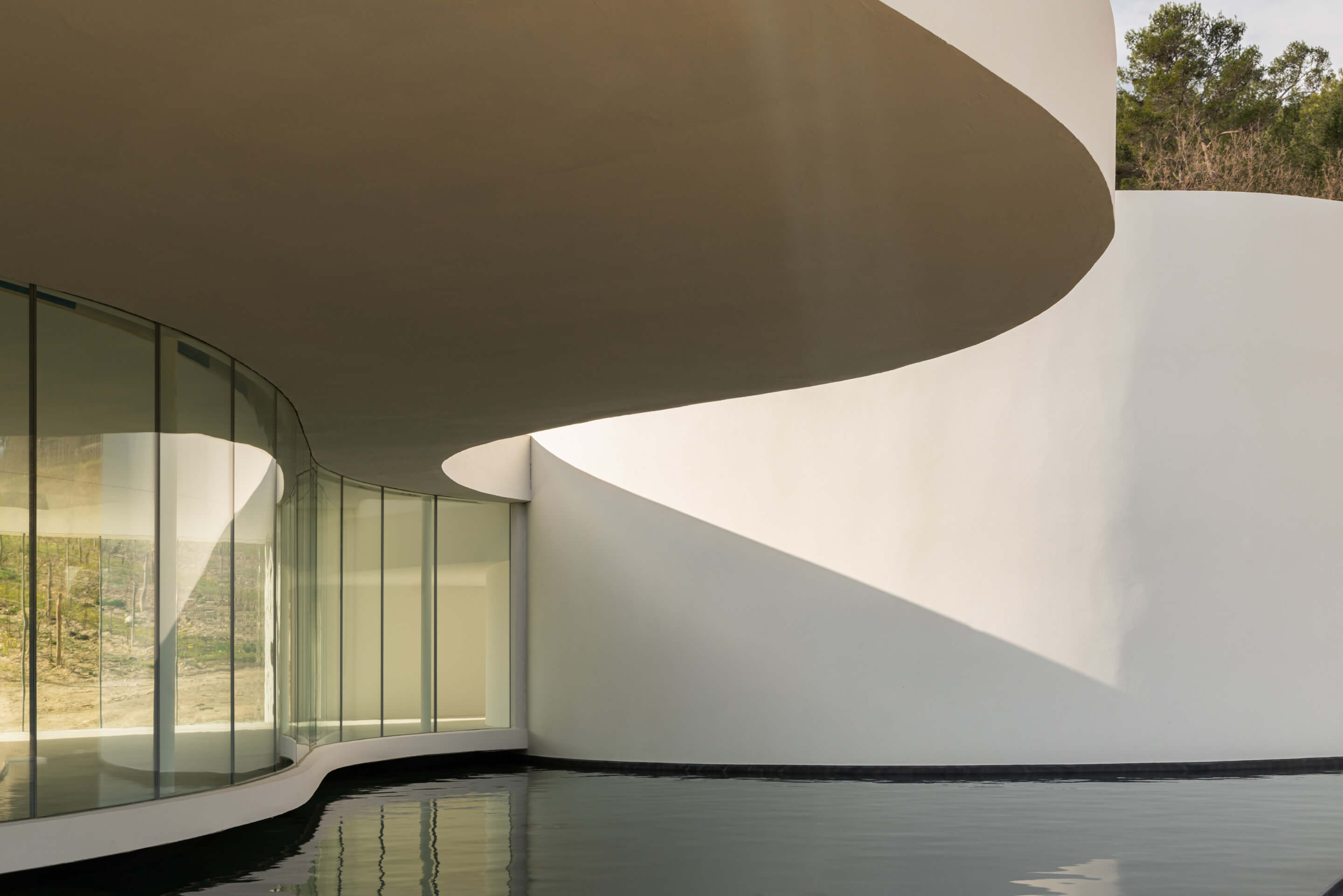 a curvy gallery space looking out to a reflecting pool