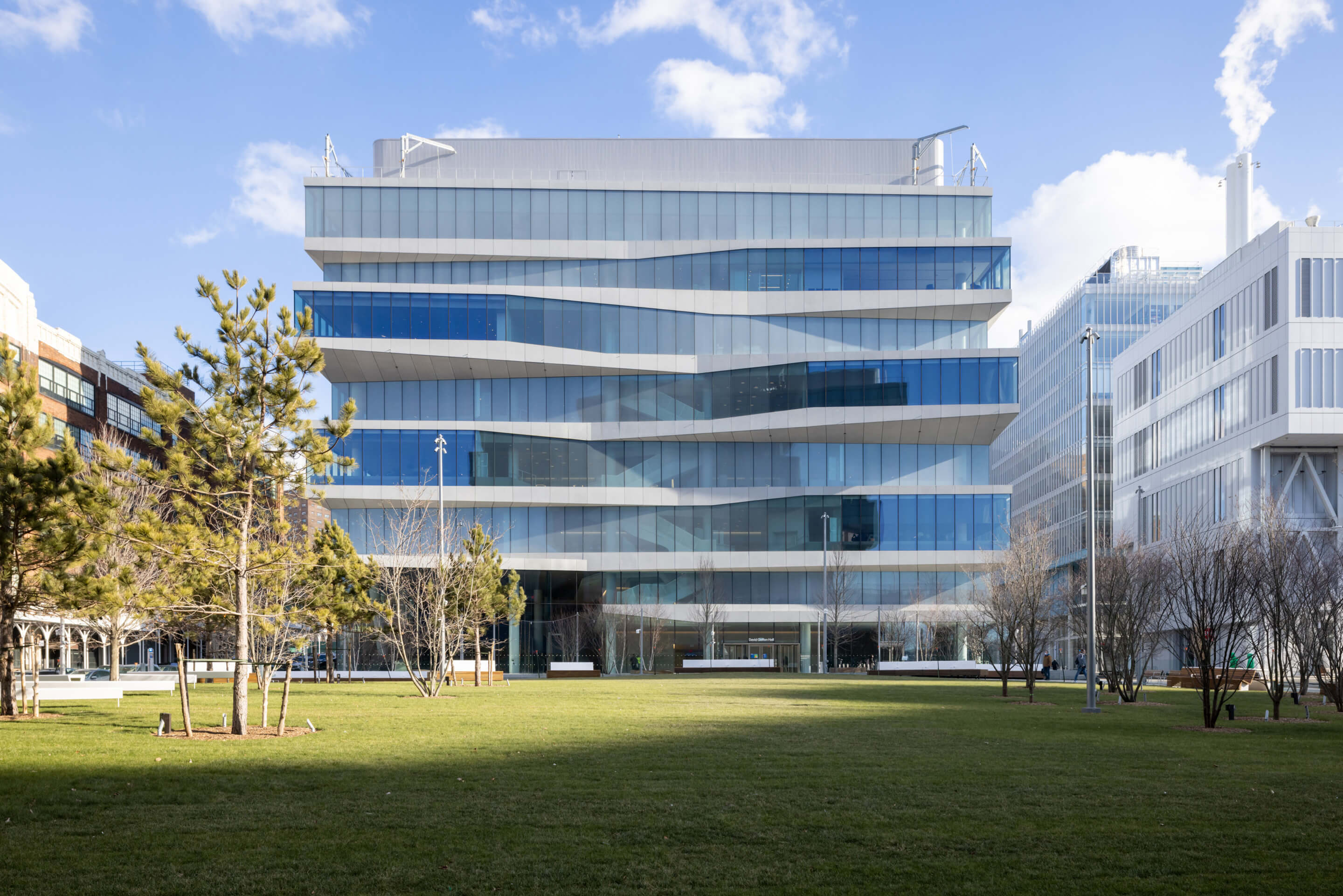 exterior view of a glassy university building fronted by a lawn