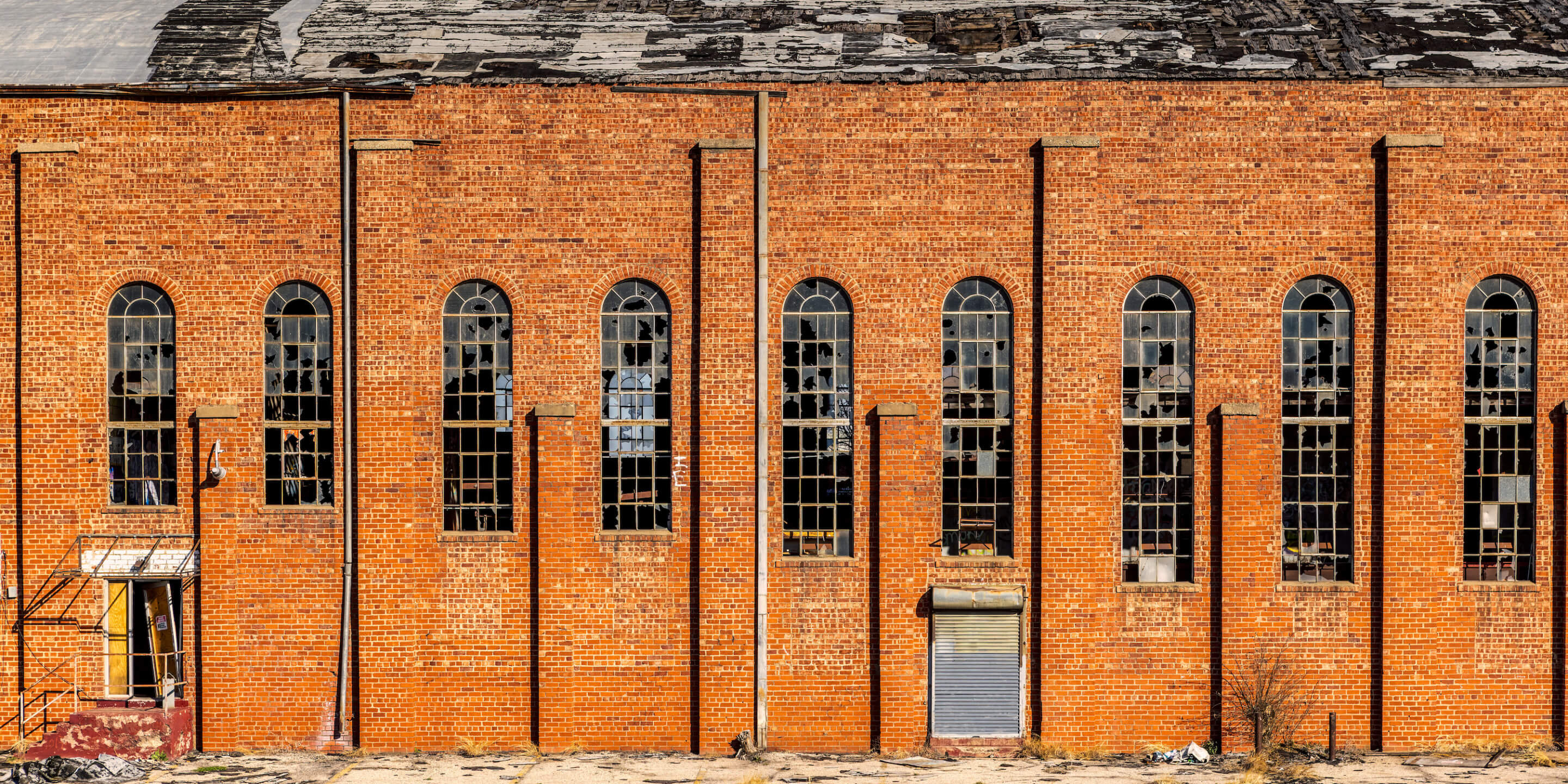 facade of a decaying brick building with broken arched windows