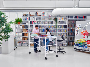 Two people working at a white desk in the middle of an office