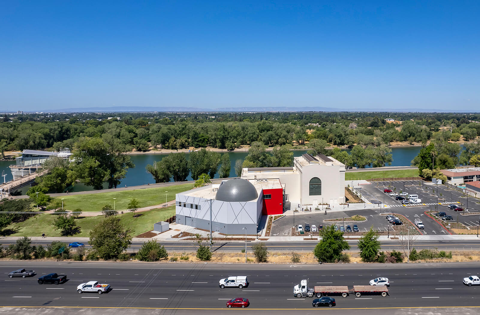 view of a freeway running alongside a riverfront science center with domed planetarium 