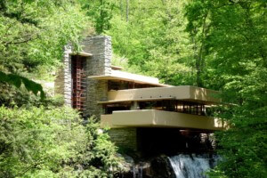 a house in the woods sitting atop a waterfall