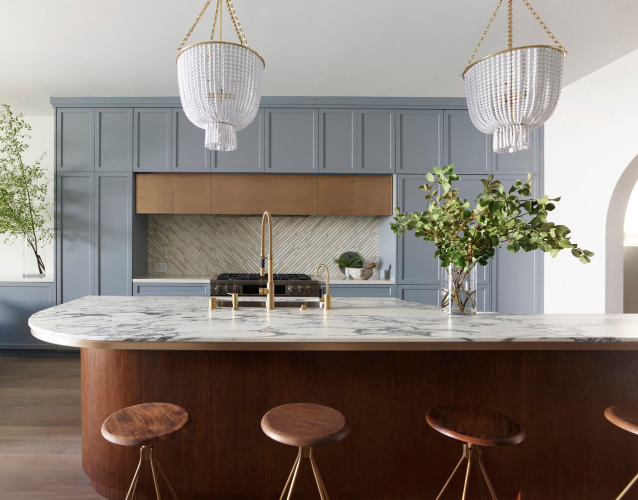 three brown stools sit under a kitchen island in a cool-toned kitchen