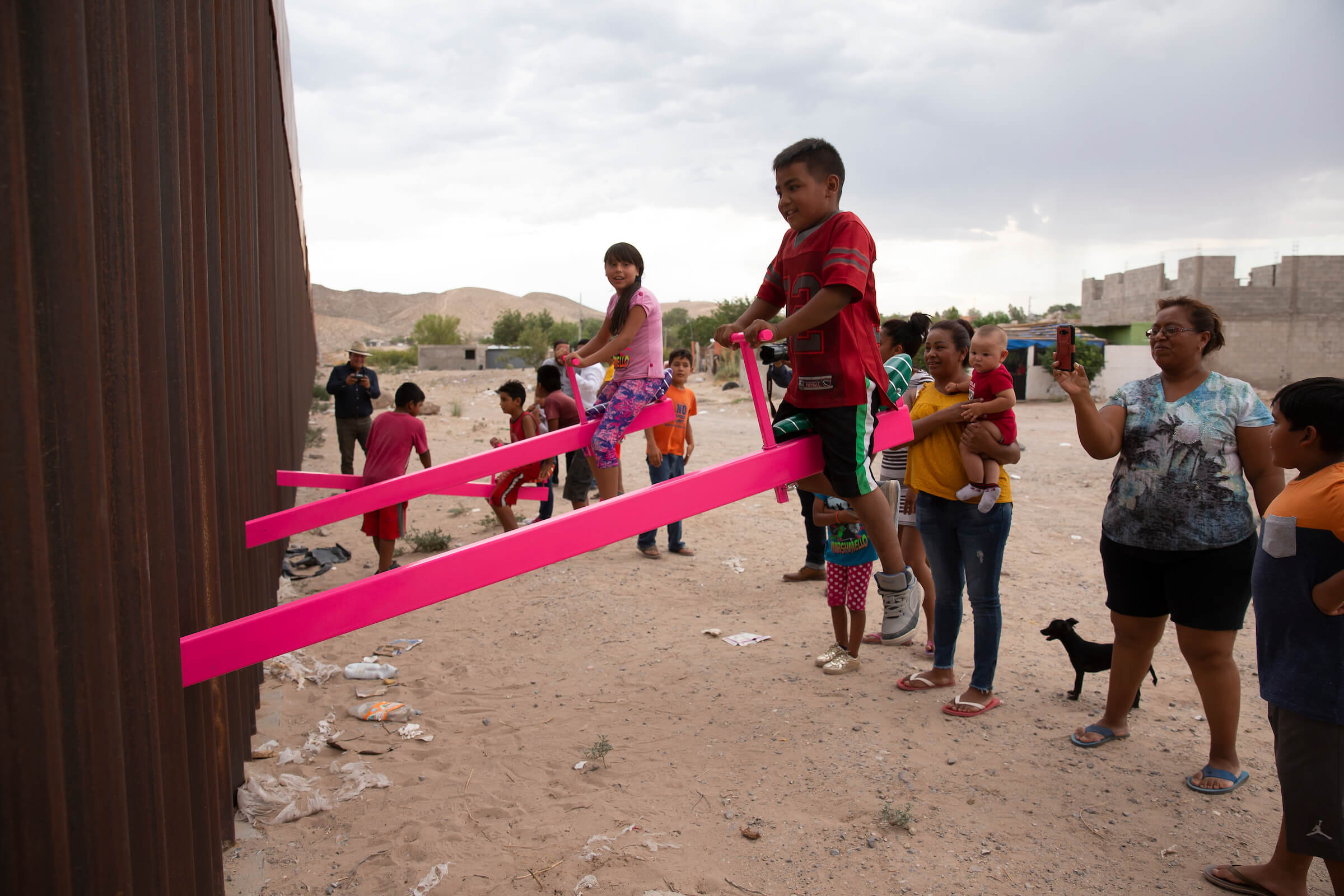 an interactive pink see-saw installation along the us-mexico border
