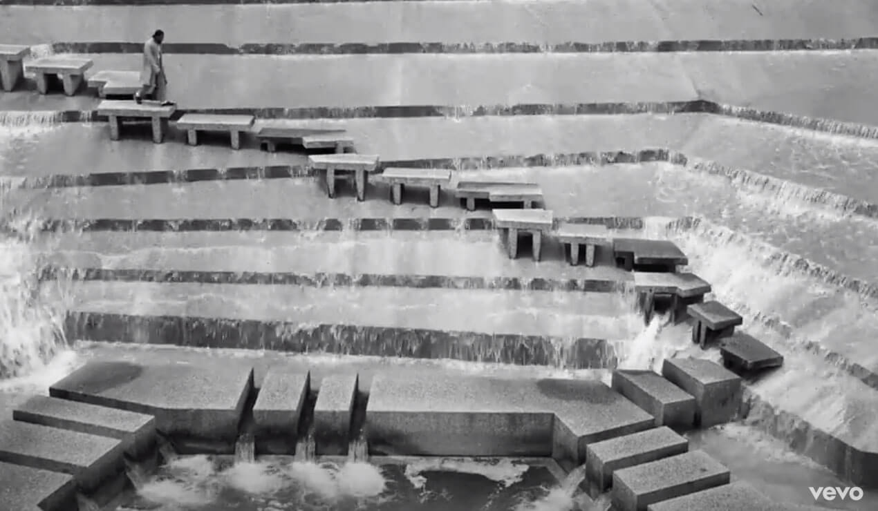 black and white shot of a man descending a concrete staircase in a waterfall
