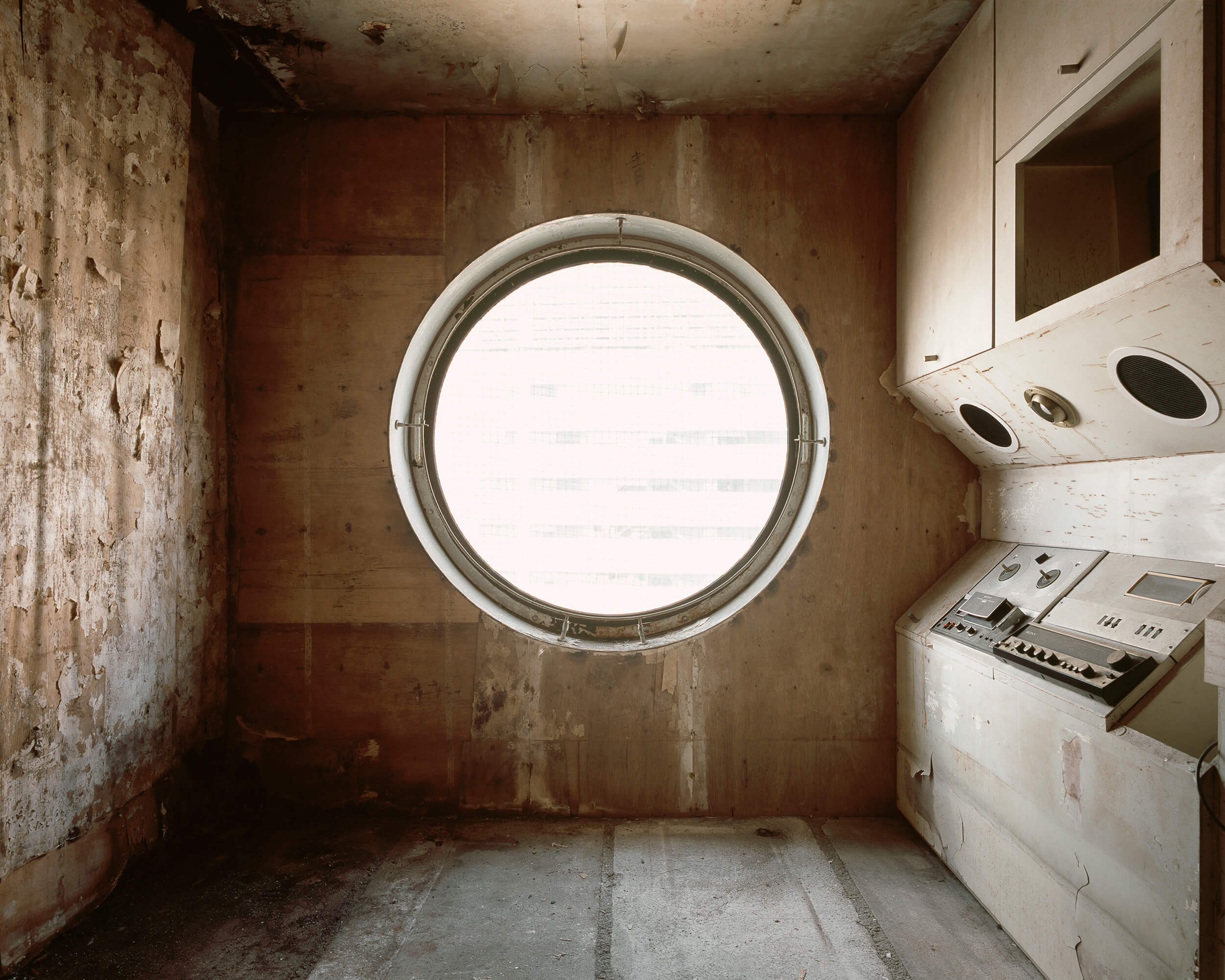 view of an abandoned, decaying living space with a large circular window