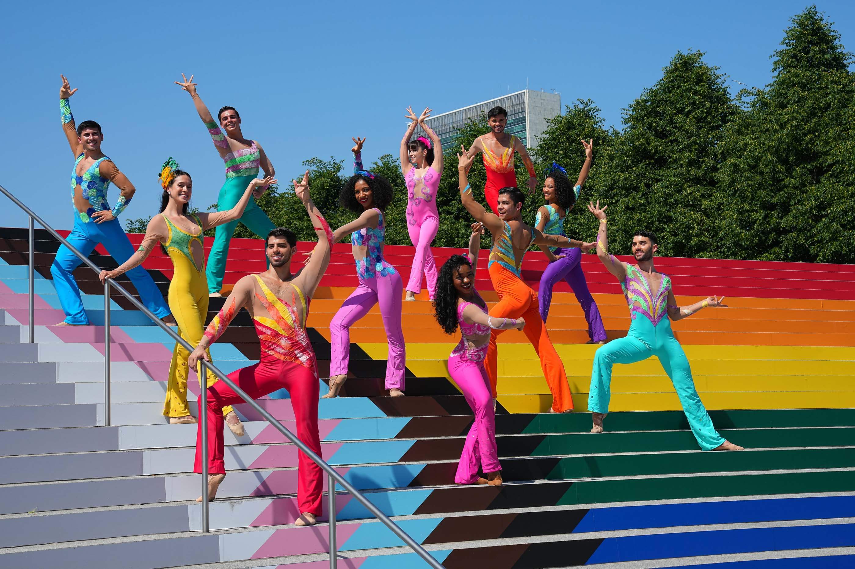 People in colorful outfits dancing on rainbow painted stairs