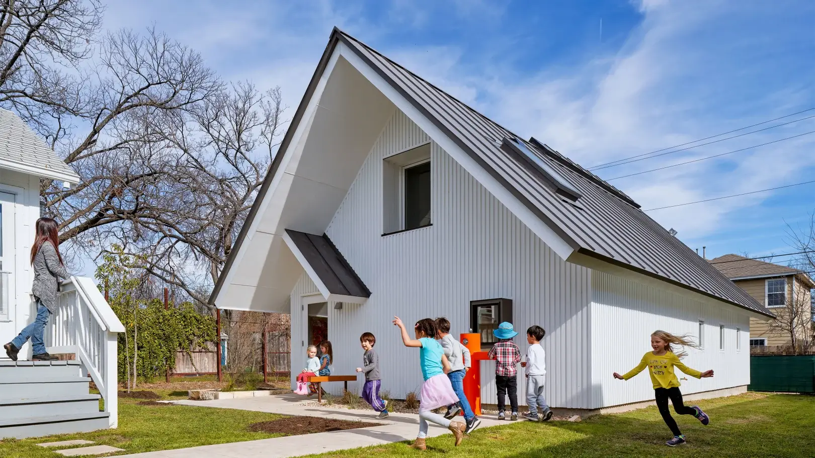 a gabled tiny house with children frolicking outside