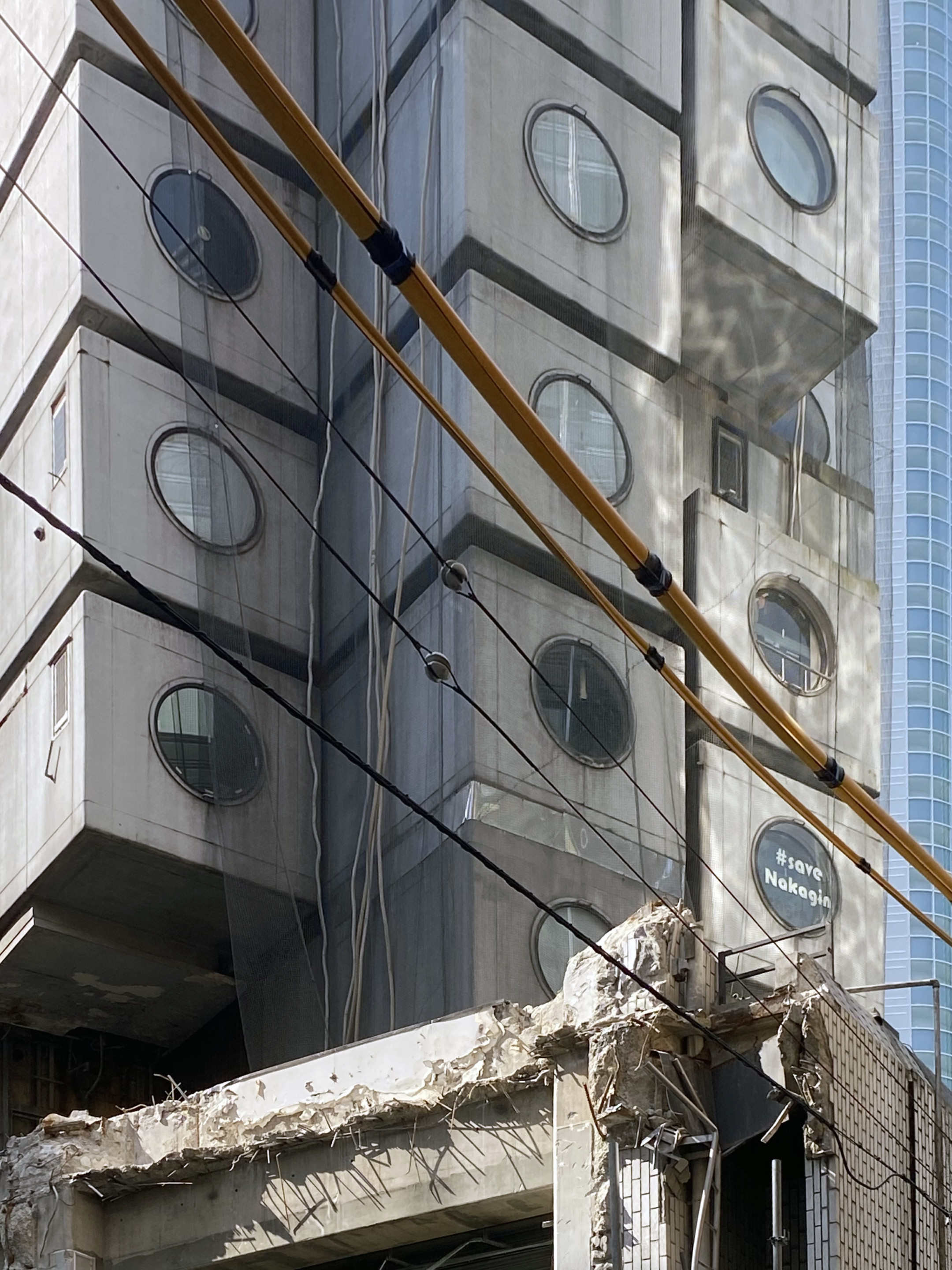 image of the crumbling nakagin capsule tower in tokyo, wrapped in netting