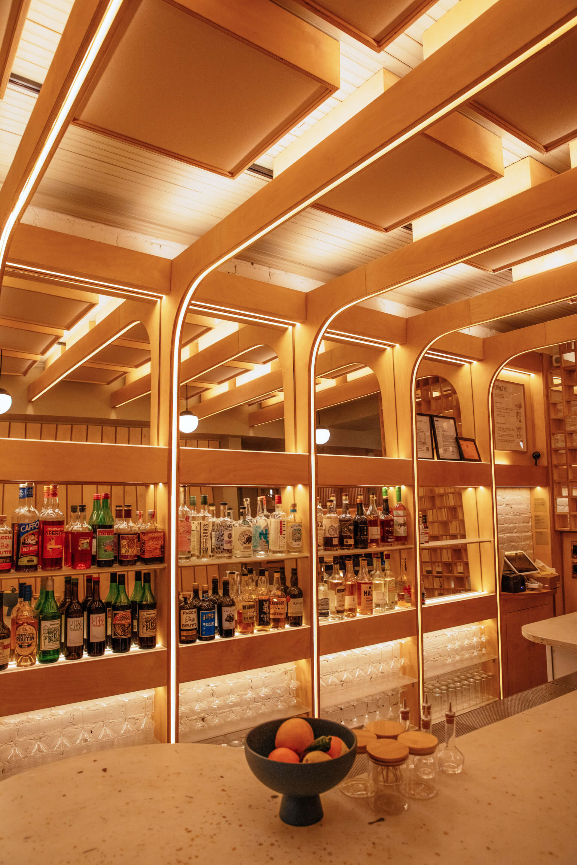 custom bar comprises a grid of reflective mirrors and wooden ribs embedded with LEDs.