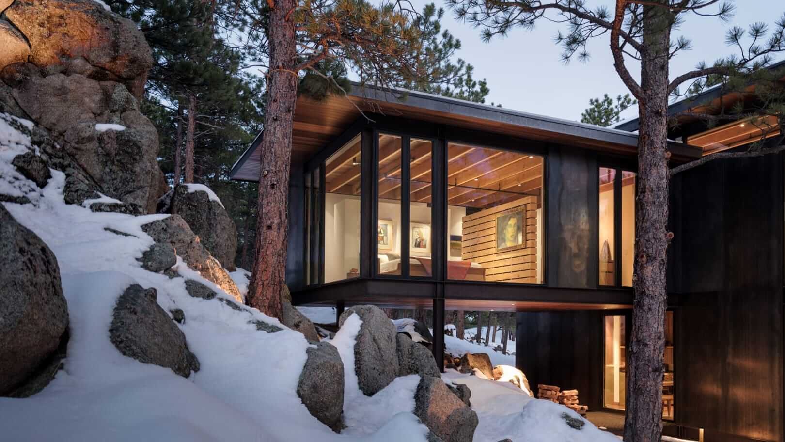 a cantilevered house nestled above a snowy landscape