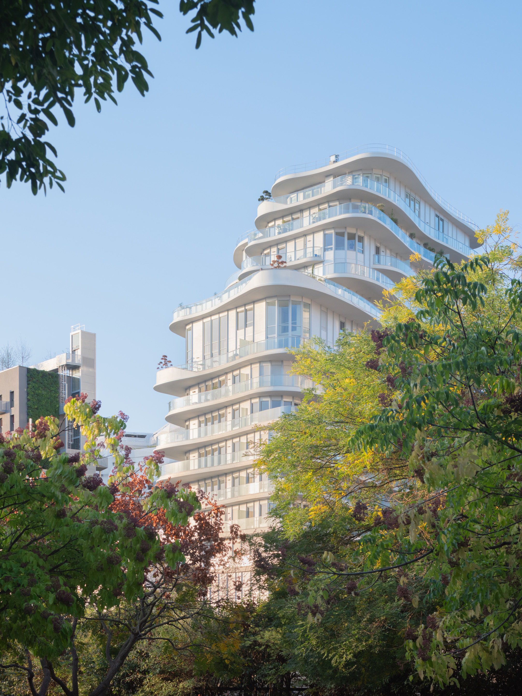 view of a balcony-wrapped apartment building through trees
